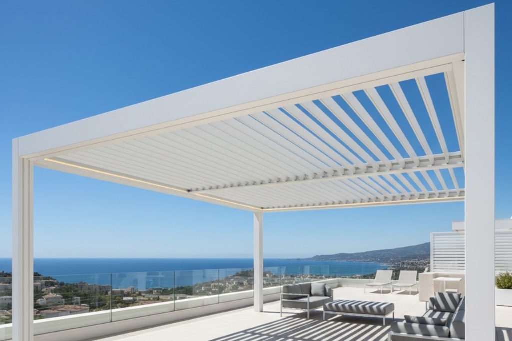 Elegante terraza moderna con pérgola blanca y vista panorámica al mar y la costa.